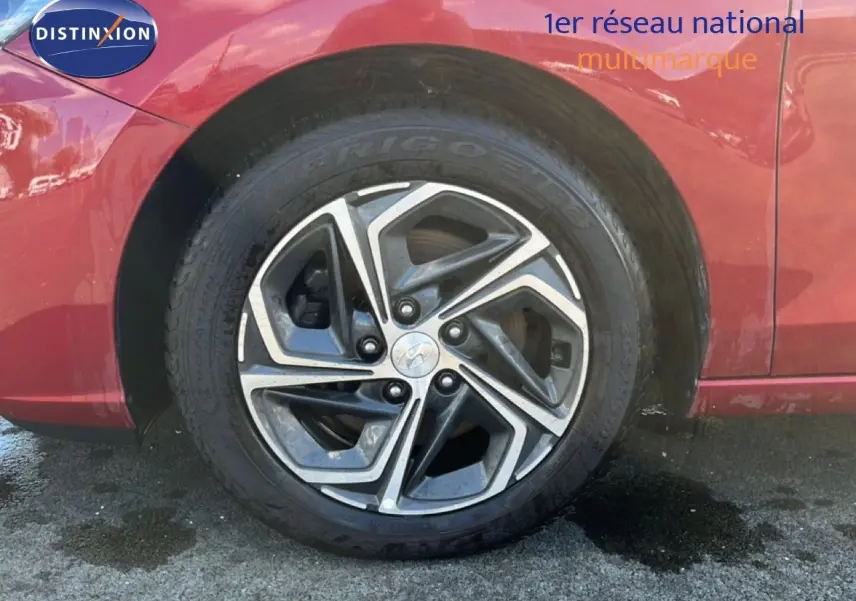 Gros plan sur la roue arrière droite d'une Hyundai i30 SW 2023 rouge Sunset Red Metal avec jante alliage bicolore.