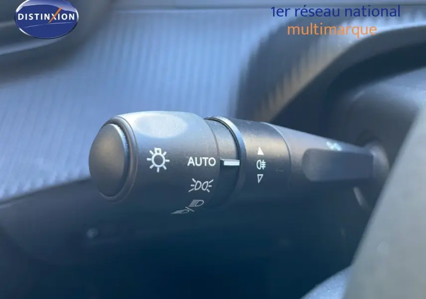 Gros plan sur la commande des phares de la Peugeot 208 Hybrid 110ch Allure, intérieur noir, détails des symboles lumineux.