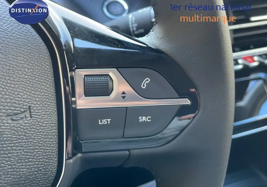 Gros plan sur les commandes au volant à droite d’un Peugeot 208 noir Perla Metal, avec tableau de bord en arrière-plan.