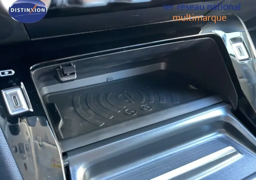 Gros plan sur le compartiment de recharge sans fil au centre de la console d’une Peugeot 208 Hybrid 110ch noire.