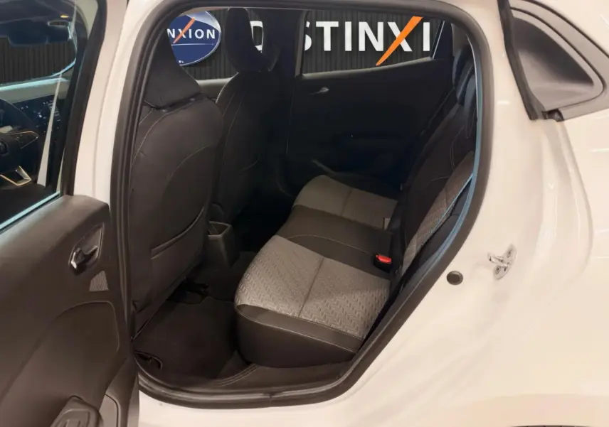 Vue côté droit arrière de l'intérieur d'une Renault Clio V blanche, montrant les sièges arrière en tissu gris et noir.