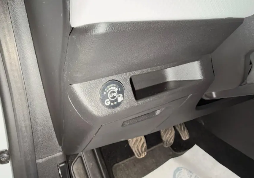 Détail intérieur montrant le bouton de sélection GPL sous le tableau de bord côté conducteur de la Renault Clio V blanche.