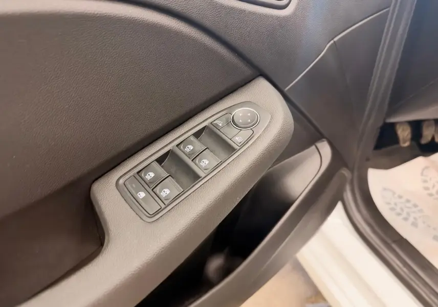 Gros plan sur la commande des vitres côté conducteur de la Renault Clio V blanche, avec portière ouverte.
