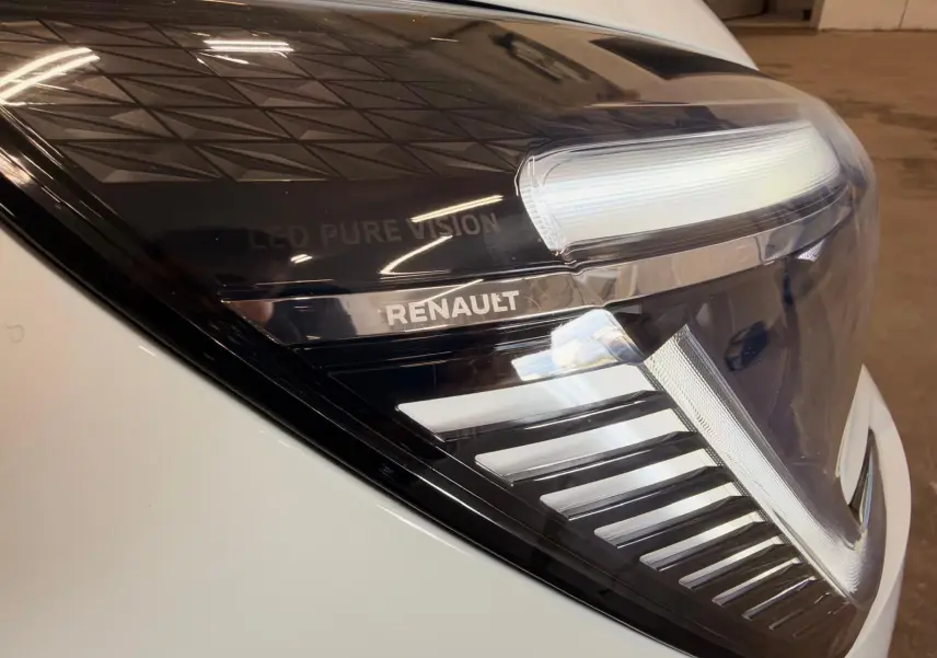 Gros plan sur le phare avant droit blanc de la Renault Clio V avec marquage LED Pure Vision et logo Renault visible.