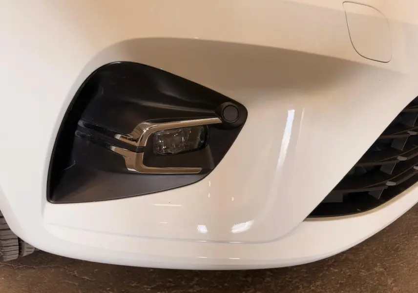 Gros plan sur le feu antibrouillard avant gauche de la Renault Clio V blanche, avec détails chromés et calandre partielle visible.