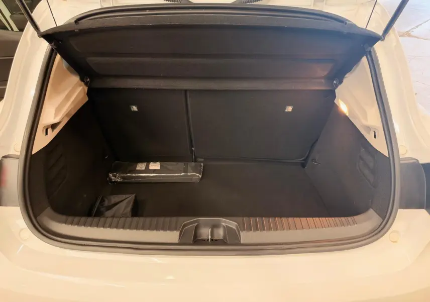 Coffre ouvert d'une Renault Clio V blanche, vue arrière, montrant un espace de rangement propre et éclairé.