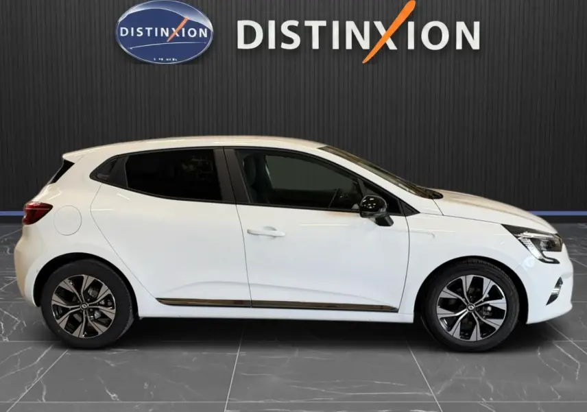 Profil droit d'une Renault Clio V blanche 5 portes de 2023, avec jantes bi-ton et vitres teintées.
