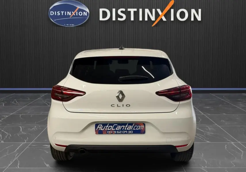 Vue arrière d'une Renault Clio V blanche, avec feux LED et logo distinctif sur fond intérieur showroom.