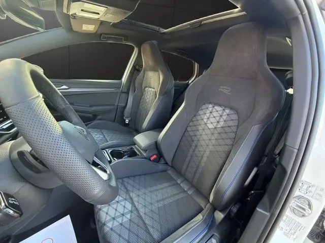 Vue intérieure côté conducteur de la Volkswagen Golf 2.0 TDI blanche, sièges sport R-Line en tissu et alcantara avec surpiqûres bleues.