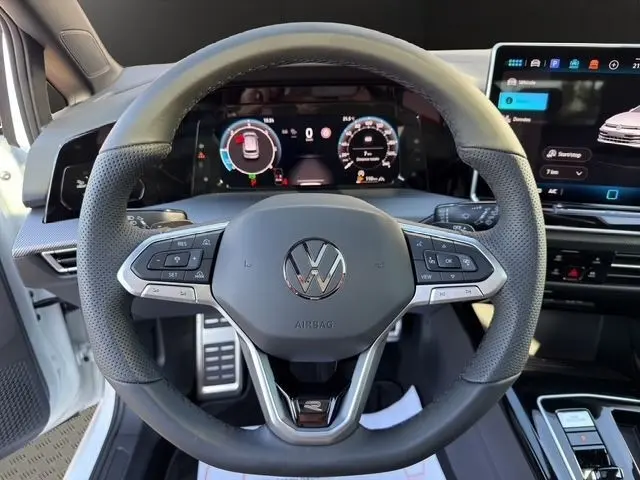 Vue centrée sur le volant cuir noir de la Volkswagen Golf blanche 2025 avec tableau de bord numérique et écran tactile.