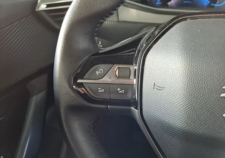 Gros plan sur les commandes gauche du volant en cuir noir du Peugeot 2008 1.2 PureTech 100 Allure 2020.
