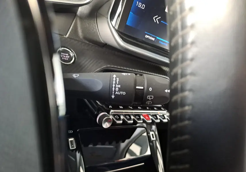 Gros plan sur la commande d'essuie-glace et le bouton start/stop du tableau de bord noir d'un Peugeot 2008 2020.