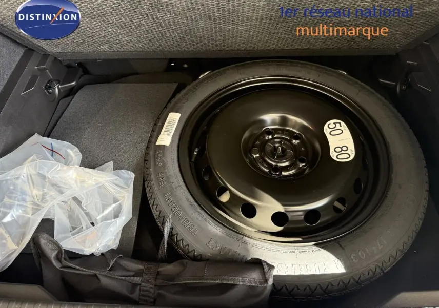 Vue du coffre avec roue de secours noire et accessoires de bord dans un Renault Captur gris Cassiopée métal toit gris.