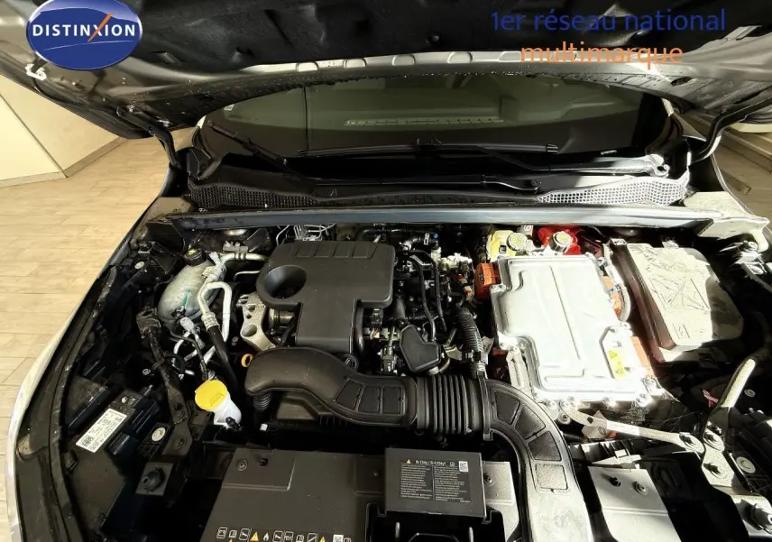 Vue rapprochée du moteur hybride sous capot ouvert du Renault Captur gris Cassiopée, montrant les composants techniques.