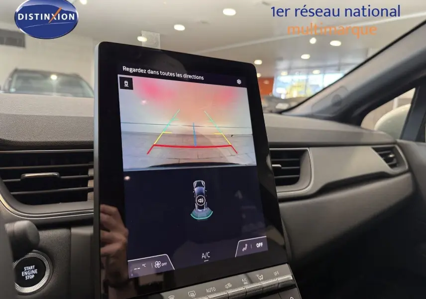 Vue intérieure du tableau de bord du Renault Captur 2025, écran tactile affichant la caméra de recul et les commandes climatisation.