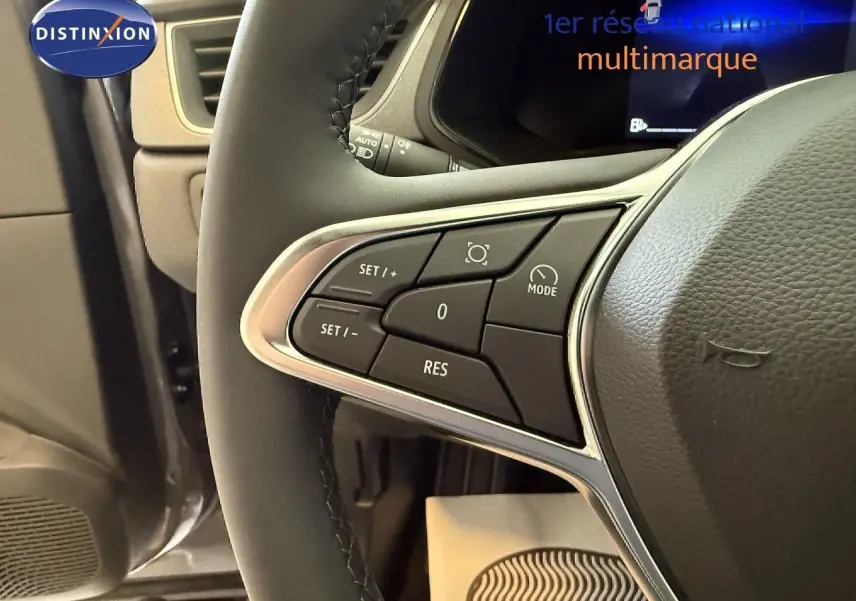 Gros plan sur les commandes au volant du Renault Captur 2025, version hybride, avec finition cuir gris et affichage digital en arrière-plan.