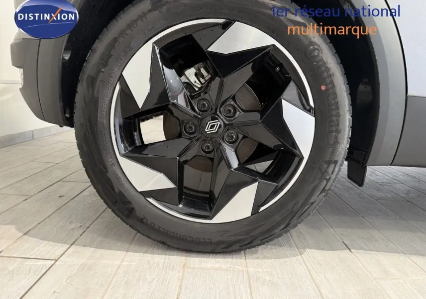 Gros plan sur la roue avant droite du Renault Captur gris Cassiopée, mettant en valeur la jante noire et argentée au design géométrique.