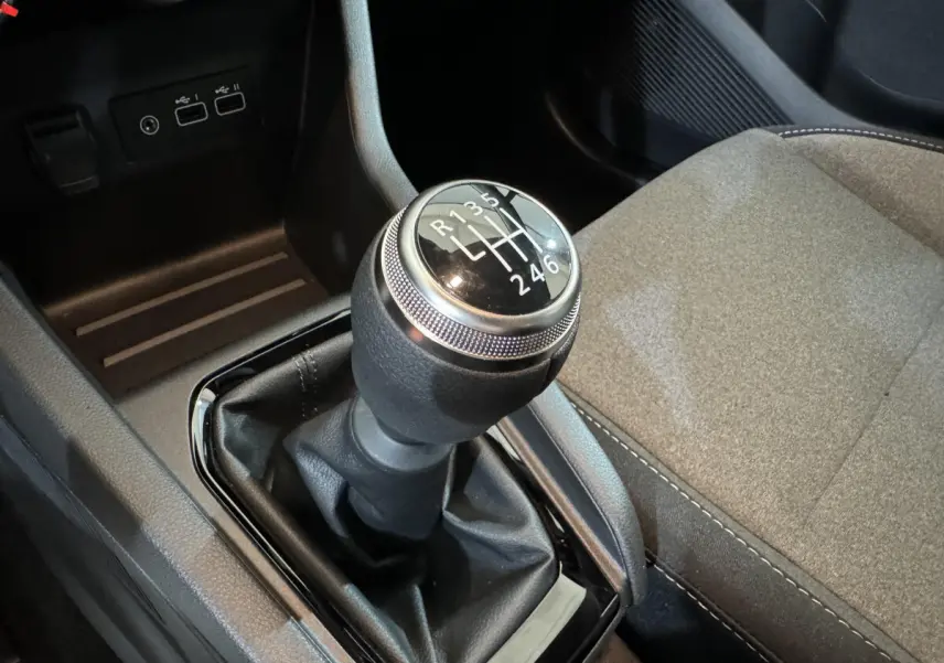 Le levier de vitesses manuel en gros plan dans l'habitacle de la Renault Clio gris clair, avec siège tissu visible.