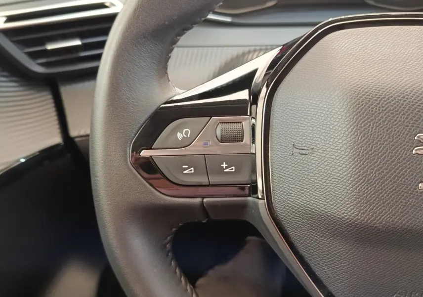 Gros plan sur le volant cuir noir de la Peugeot 208 PureTech 75 S&S Style 2023 avec commandes multifonctions.