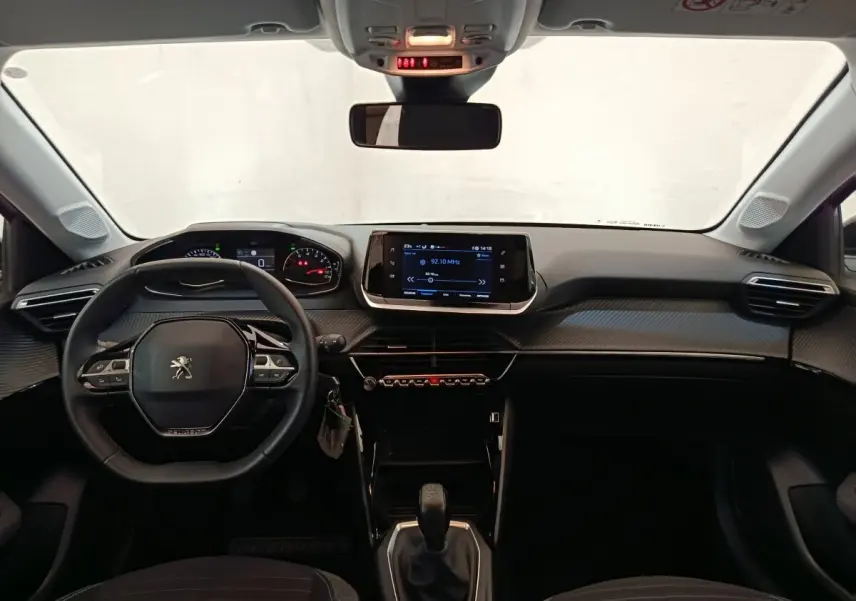 Vue intérieure frontale du tableau de bord noir de la Peugeot 208 PureTech 75 S&S Style avec écran tactile central et volant cuir multifonctions.