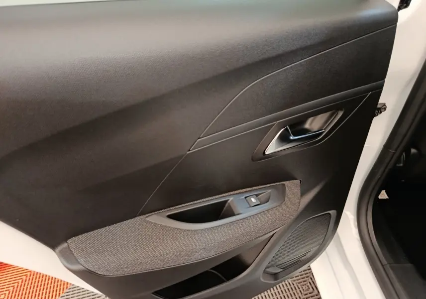 Vue intérieure de la porte avant droite noire et grise de la Peugeot 208 PureTech 75 S&S Style 2023, avec bouton de lève-vitre.