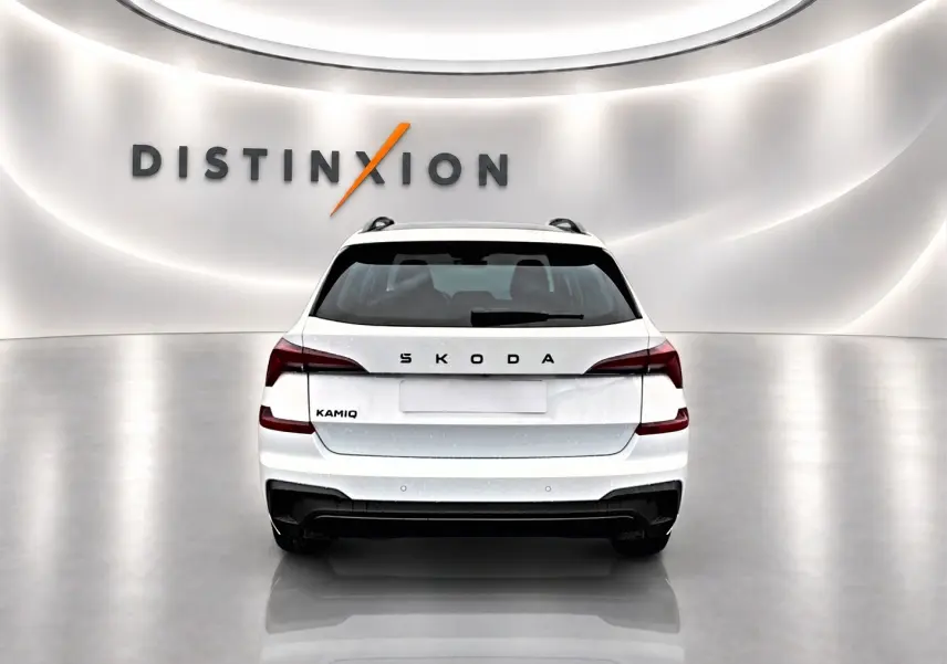 Vue arrière d’un Skoda Kamiq blanc nacré avec feux arrière LED et diffuseur noir dans un showroom lumineux.