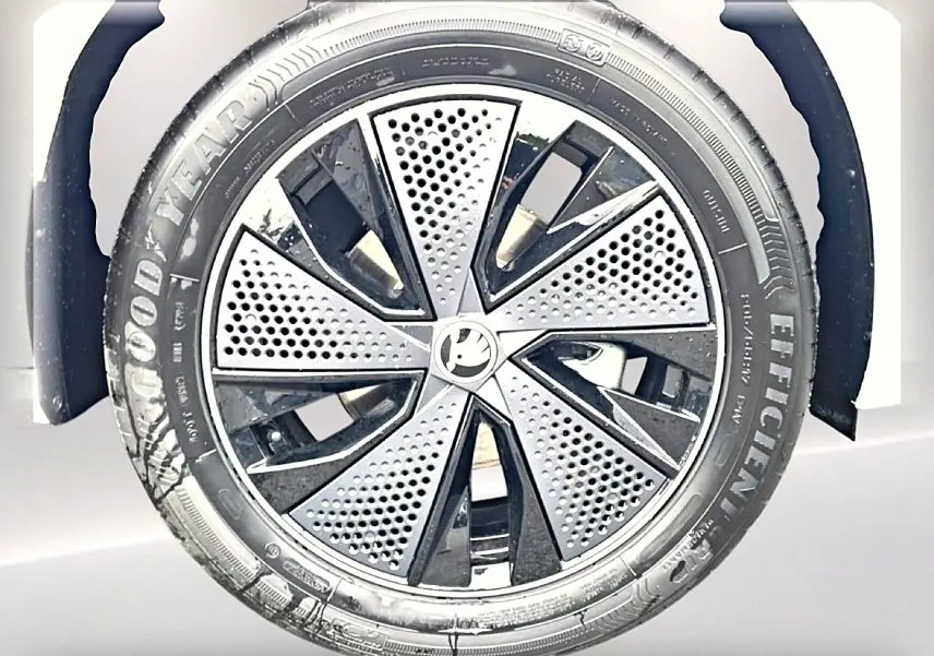Gros plan sur la roue avant droite d’un Skoda Kamiq blanc nacré avec jante alu noire et argentée au design perforé.