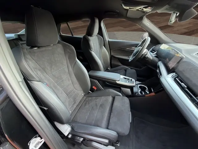 Vue intérieure côté conducteur de la BMW X2 sDrive20d M Sport 2025 noire, sièges en alcantara et cuir, volant multifonctions.
