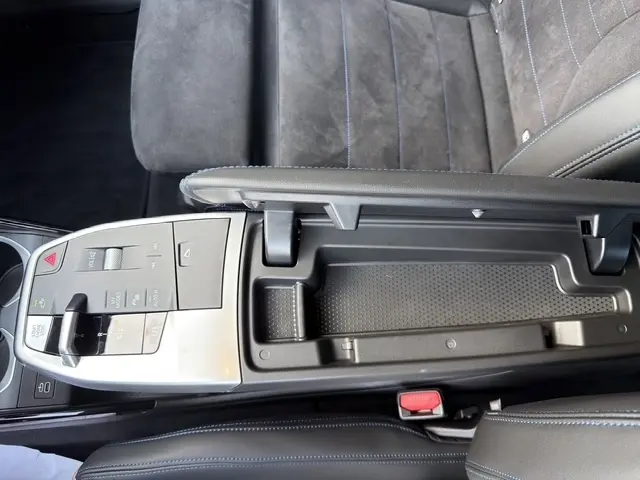 Gros plan intérieur sur la console centrale ouverte et siège en alcantara noir avec surpiqûres bleues d'une BMW X2 sDrive20d M Sport 2025.
