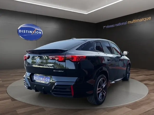 BMW X2 sDrive20d M Sport noir vue 3/4 arrière droite, avec spoiler de toit et jantes sportives visibles.