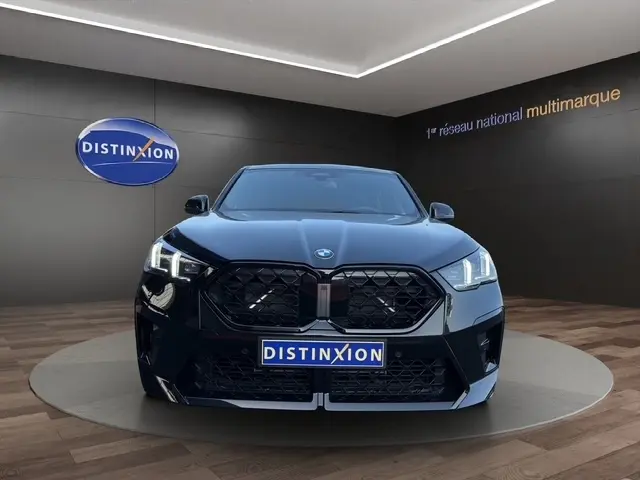 Vue frontale d'un BMW X2 sDrive20d M Sport noir avec calandre imposante et phares LED allumés en showroom.