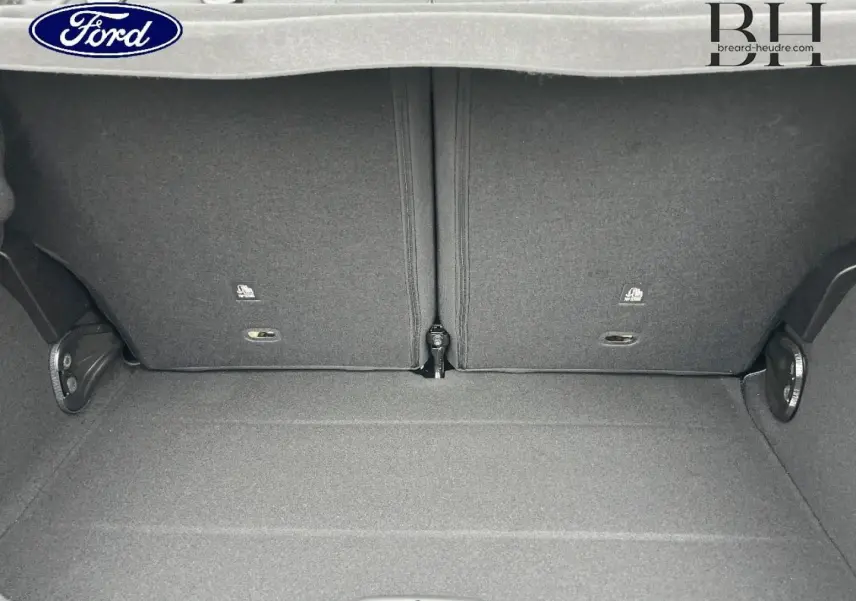 Coffre ouvert d'une FIAT 500 Ice White pastel, montrant la banquette arrière rabattable et le tapis de coffre gris.
