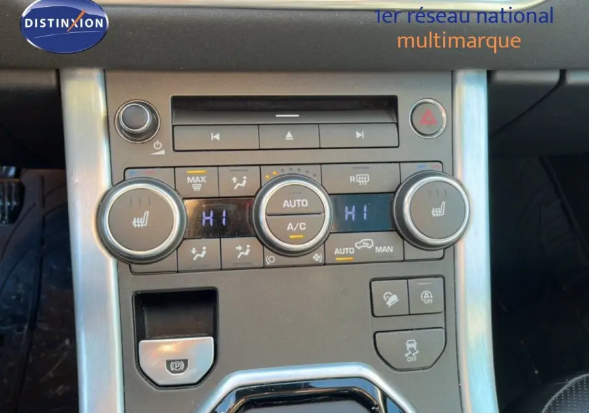 Console centrale du Range Rover Evoque blanc 2017, vue rapprochée des commandes de climatisation et du frein à main électrique.