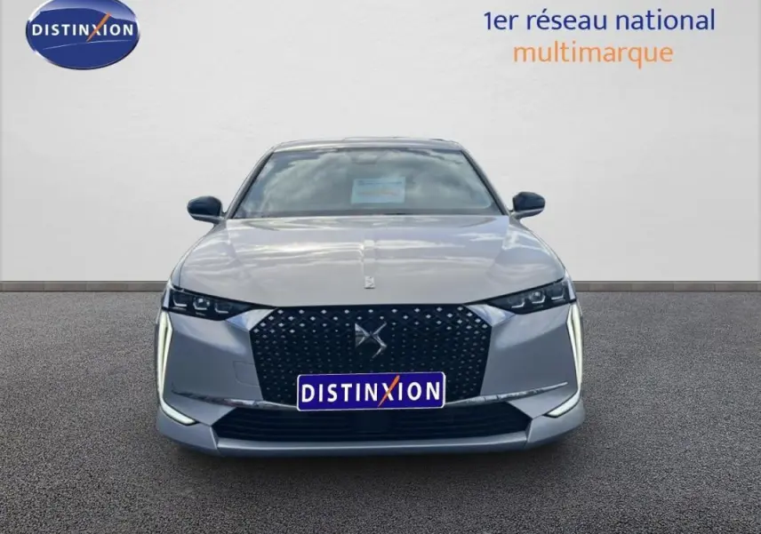 Vue frontale d'une DS4 2024 gris clair avec calandre noire à motifs et feux diurnes verticaux LED distinctifs.