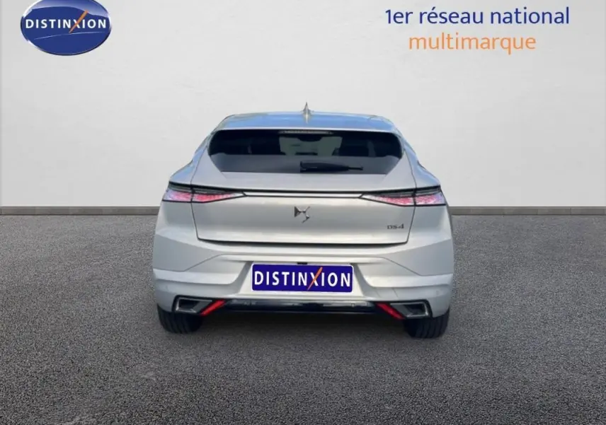 Vue arrière d'une DS4 2024 gris clair, avec feux étirés et double sortie d'échappement intégrée au pare-chocs.