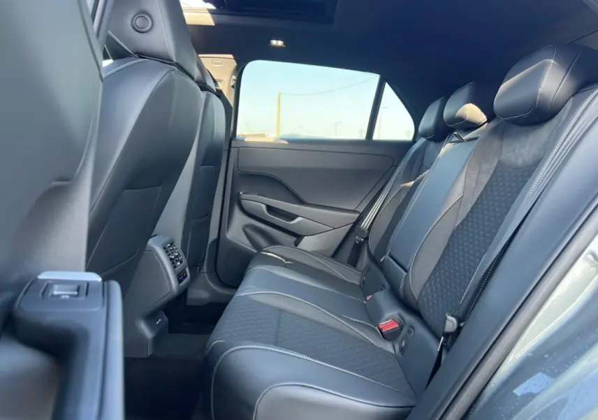 Vue intérieure arrière droite du Volkswagen T-Roc 2026 gris loup, montrant la banquette en tissu et cuir avec surpiqûres contrastées.