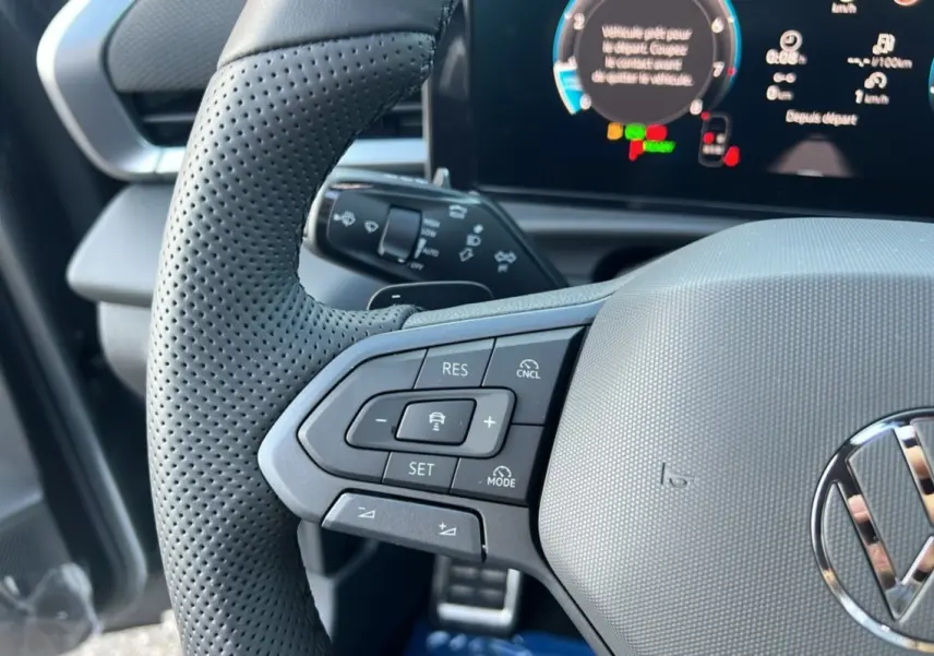 Gros plan sur le volant cuir perforé gris du Volkswagen T-Roc 2026 avec commandes multifonctions et tableau de bord digital.