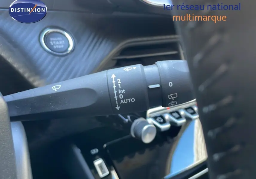 Gros plan sur la commande d’essuie-glace à gauche du volant dans l’habitacle noir de la Peugeot 208 Hybrid 110ch.