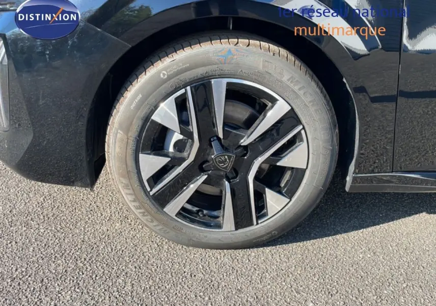 Gros plan sur la roue avant gauche noire perla metal d'une Peugeot 208 Hybrid 110ch avec jante alliage bicolore.