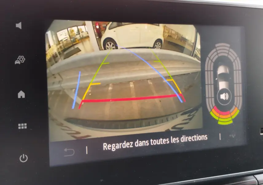 Vue de la caméra de recul du Renault Kangoo blanc minéral, avec lignes de guidage colorées et obstacle visible derrière.