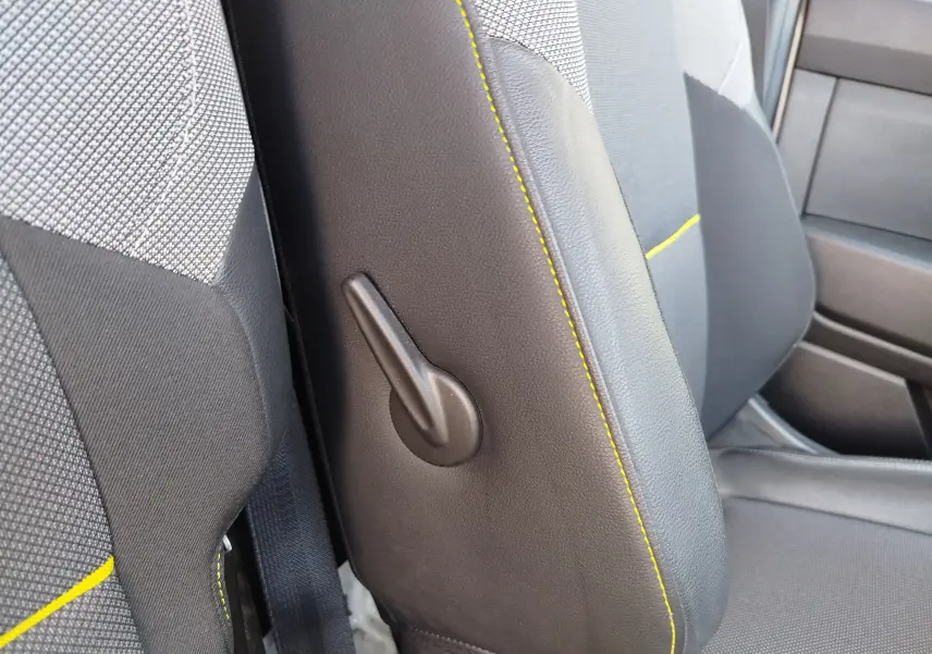 Détail de la manette de réglage latérale sur le siège avant gris foncé avec surpiqûres jaunes du Renault Kangoo blanc.
