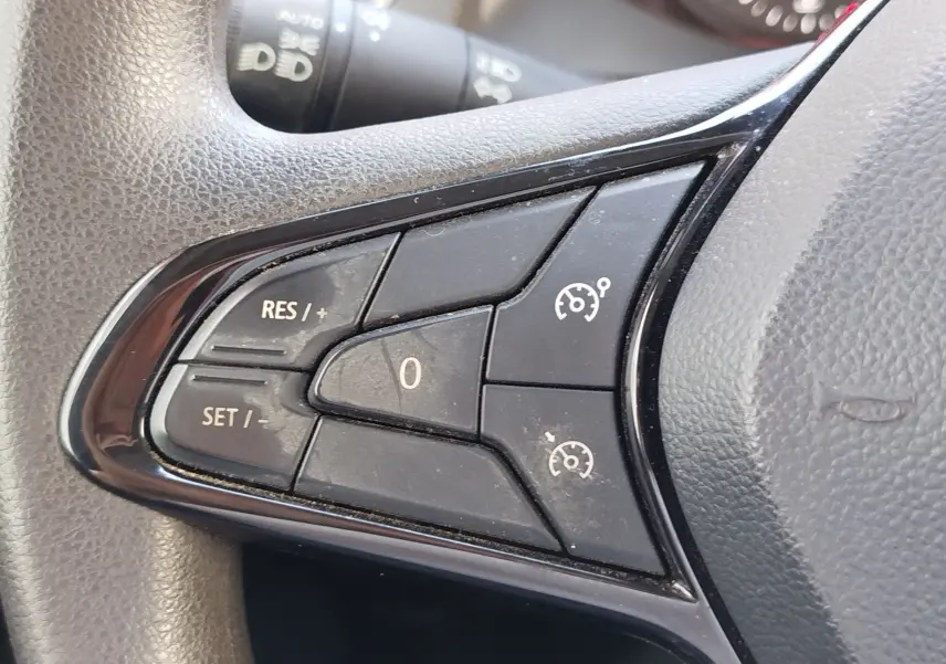 Gros plan sur les commandes de régulateur de vitesse au volant côté gauche du Renault Kangoo blanc 2023.