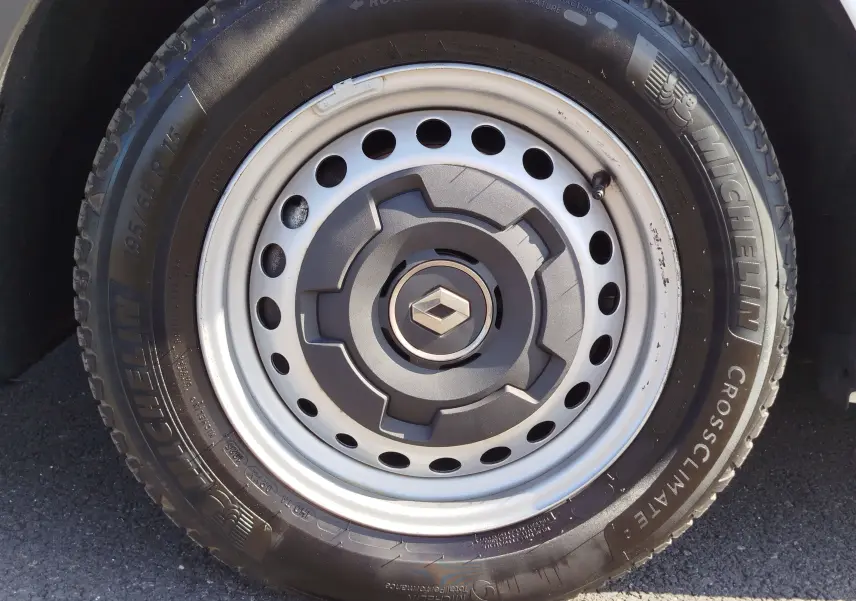 Gros plan sur la roue avant droite blanche d’un Renault Kangoo 2023 avec jante acier et pneu Michelin CrossClimate.
