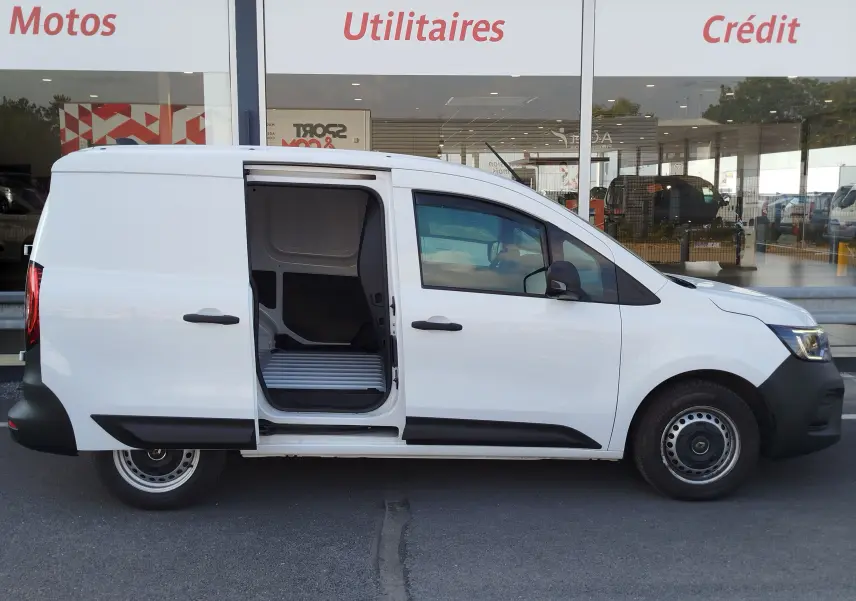 Vue latérale droite d’un Renault Kangoo blanc Minéral 2023 avec porte coulissante ouverte, montrant l’espace de chargement utilitaire.