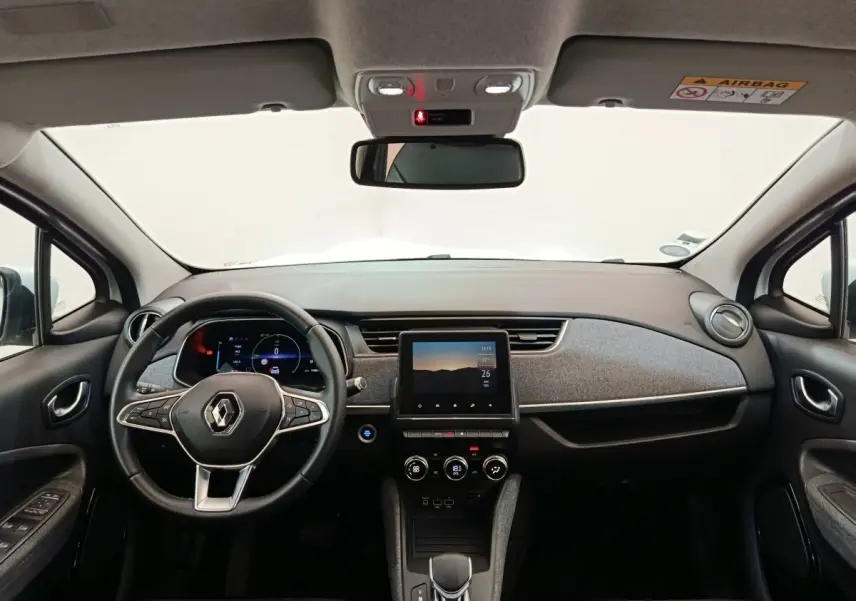Vue frontale de l'intérieur de la Renault ZOE Intens R110 blanc, avec tableau de bord moderne et écran tactile central.