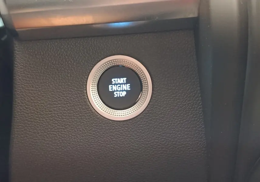 Gros plan sur le bouton démarrage "Start Engine Stop" entouré d'une bague argentée dans l'habitacle noir du Renault ZOE blanc.