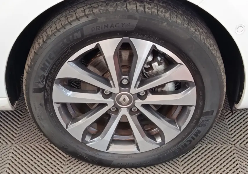 Gros plan sur la roue avant droite blanche d'une Renault ZOE Intens R110 avec jante alliage et logo Renault central.
