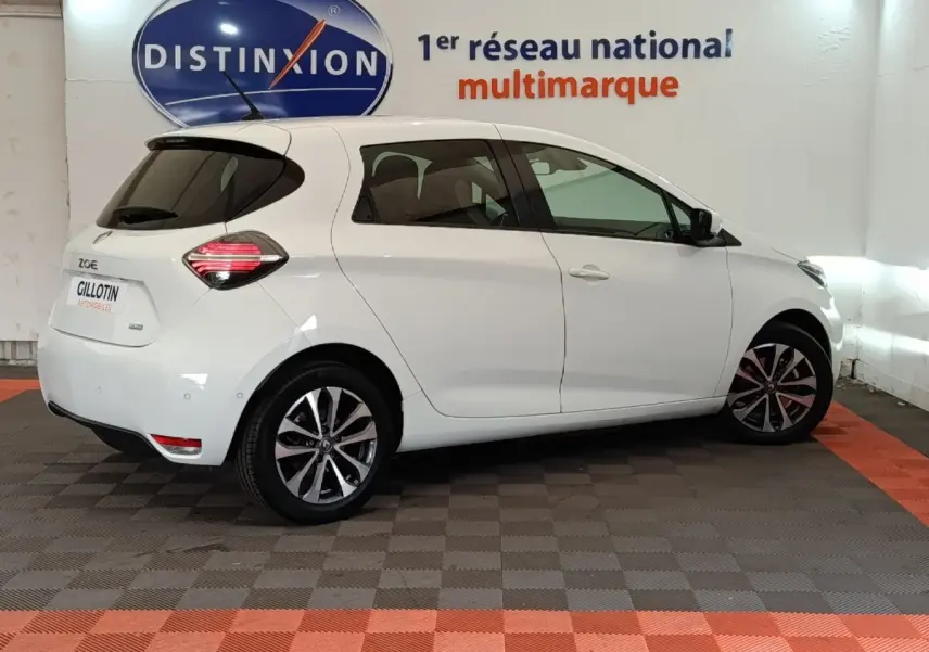 Renault ZOE Intens R110 blanc vue de profil côté droit en intérieur avec jantes alliage et feux arrière LED allumés.