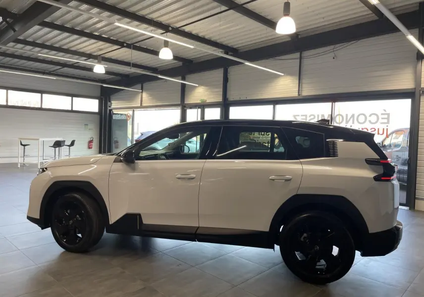 Vue de profil côté gauche d'un Citroën C5 Aircross blanc Okenite avec toit noir et jantes noires en intérieur showroom.