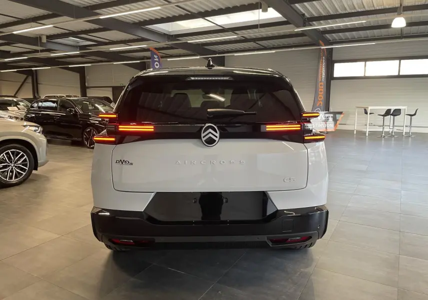 Vue arrière d'un Citroën C5 Aircross blanc Okenite avec toit noir et feux arrière LED allumés en intérieur.